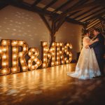 Bride and groom dancing at illuminated wedding venue.